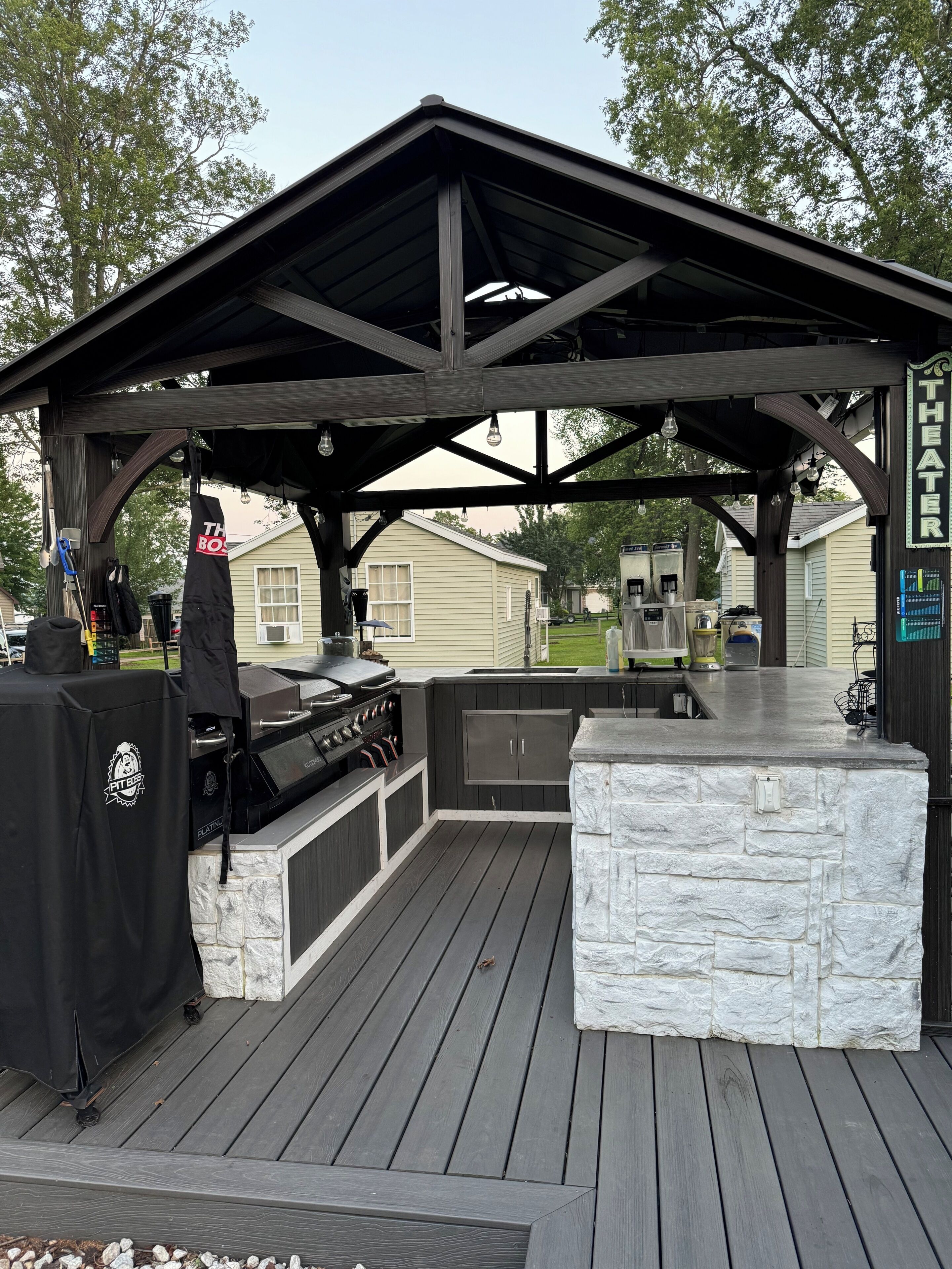 An outdoor patio with a grill, stone seating, and a covered area labeled 'THEATER'.