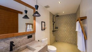 Un bany amb un gran mirall, un lavabo, un vàter i una zona de dutxa.