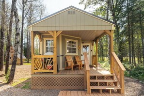 A wooden cabin with a porch, two chairs, and a bicycle rack. - Flowing Waters Retreat - Two Cabins with Sauna (Two Harbors)