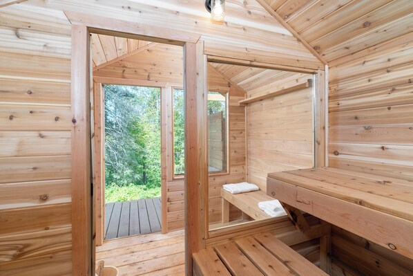 A wooden cabin with a sauna, a bench, and a window overlooking greenery. - Flowing Waters Retreat - Two Cabins with Sauna (Two Harbors)