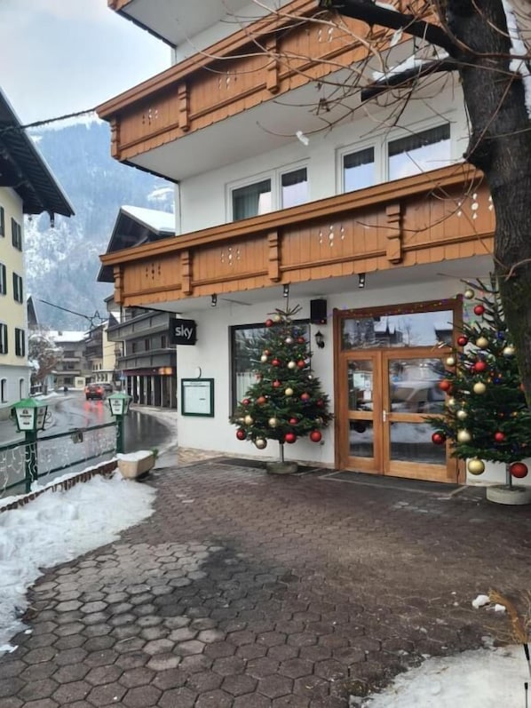A hotel with a wooden balcony, two Christmas trees, and a sign that reads 'Sky.'
