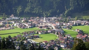 A town with a prominent church, green fields, and residential buildings.