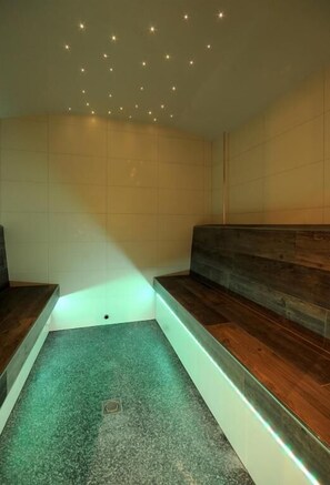 Um espaço de spa com um banco de madeira, uma pequena piscina e um teto com luzes delicadas.