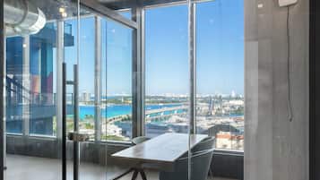 A modern office space with large windows, a glass partition, and a view of a marina and cityscape.
