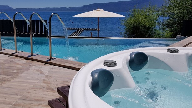 A pool area with a hot tub, a poolside deck, and a view of the sea. - Incredible apartment on the shores of Lake Villarrica!!! fully equipped!!! (Pucon)