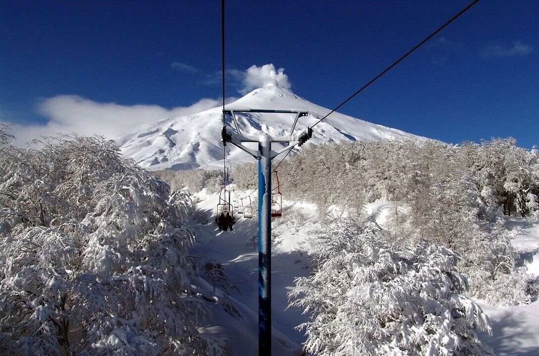 A snow-covered mountain with a ski lift in the foreground.