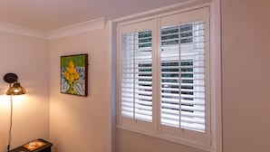 A room with a window with blinds, a wall-mounted lamp, and a framed artwork. - Cosy 2 Bed Viking Bay Cottage (Broadstairs)