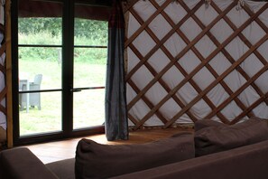 Une pièce dotée d’une grande fenêtre, d’un mur décoré d’un treillis en bois et d’un canapé marron.