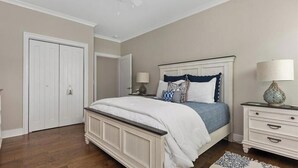 A bedroom with a bed, nightstands, a lamp, a ceiling fan, and a door. - Residence 201N at The Sandcastle Condominiums (Wildwood Crest)