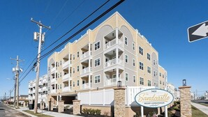 A multi-story residential building with balconies, a sign indicating 'The Sandcastle Resort Condominium,' and a clear sky. - Residence 201N at The Sandcastle Condominiums (Wildwood Crest)