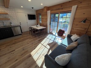 A modern interior with a dining area, sofa, and kitchen. - Deluxe Lodge Lakefront On Lake George #11 (Lake George)
