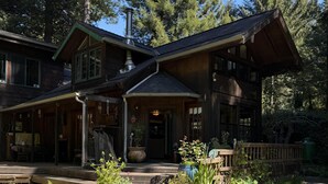 Une grande maison en bois avec un porche, une cheminée et un jardin.