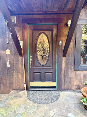 A wooden door with a glass panel, a number '452' above it, and a doormat with a decorative design.