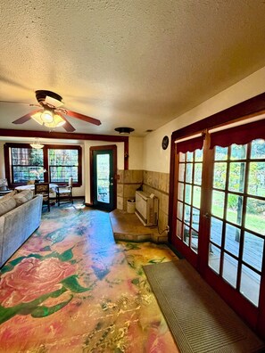 A room with a ceiling fan, a patterned floor, a sofa, a dining table, and large windows with a view.