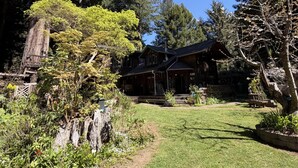 Une maison avec une pelouse bien entretenue, entourée d’arbres et d’un mur de pierres.