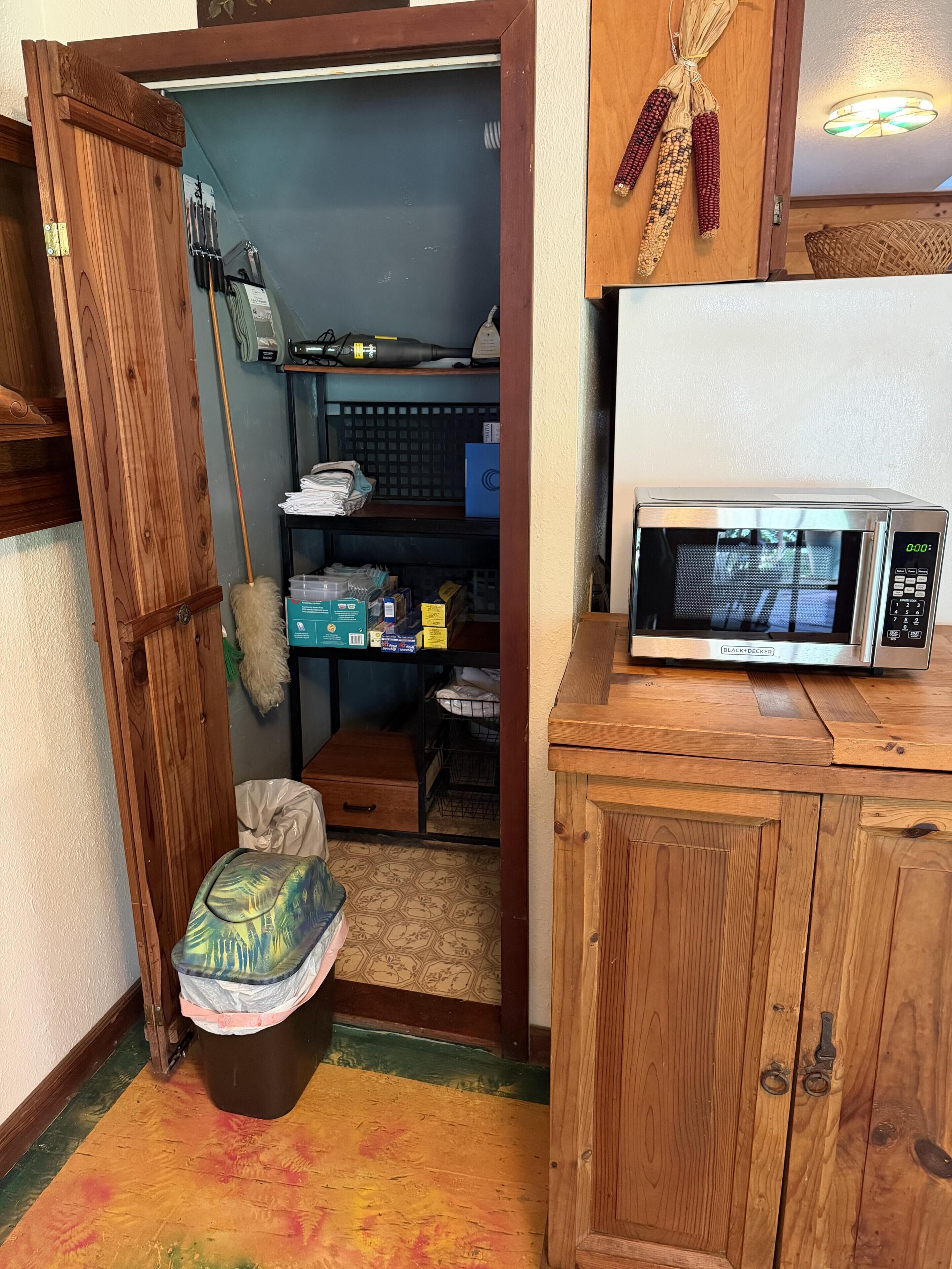 Une cuisine compacte équipée d’un four à micro-ondes, de meubles en bois et d’un petit espace de rangement avec des étagères.