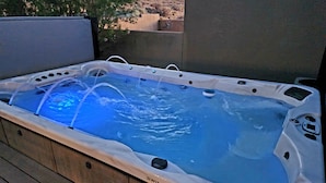 Un bain à remous doté d’un système de filtration à eau claire, entouré d’une terrasse en bois.