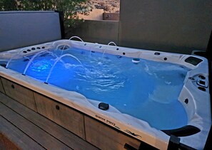 A hot tub with a clear water feature, surrounded by a wooden deck. - The Desert Dip Oasis at Lake Powell with swim spa!
 (Page)