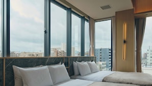 Habitación de hotel con dos camas, ventanas amplias y vista a la ciudad.
