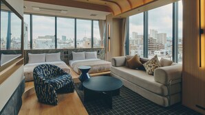 Une chambre d’hôtel moderne avec une grande fenêtre, un canapé, un lit et une table basse.
