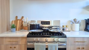 A kitchen with a stove, pots, a knife block, and a plant. - Z Haus Sedona- Hot tub, cold plunge, fire pit, EV charger (Sedona)