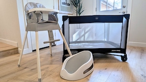 A room with a baby playpen, a high chair, and a baby walker. - Z Haus Sedona- Hot tub, cold plunge, fire pit, EV charger (Sedona)
