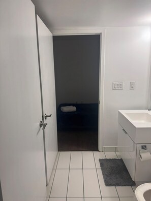 Ein Badezimmer mit einem weißen Waschbecken, einer Toilette und einem Handtuch auf dem Boden.