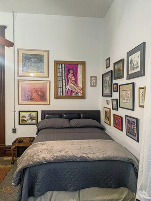 A bedroom with a bed, a nightstand, and a wall adorned with framed artwork.