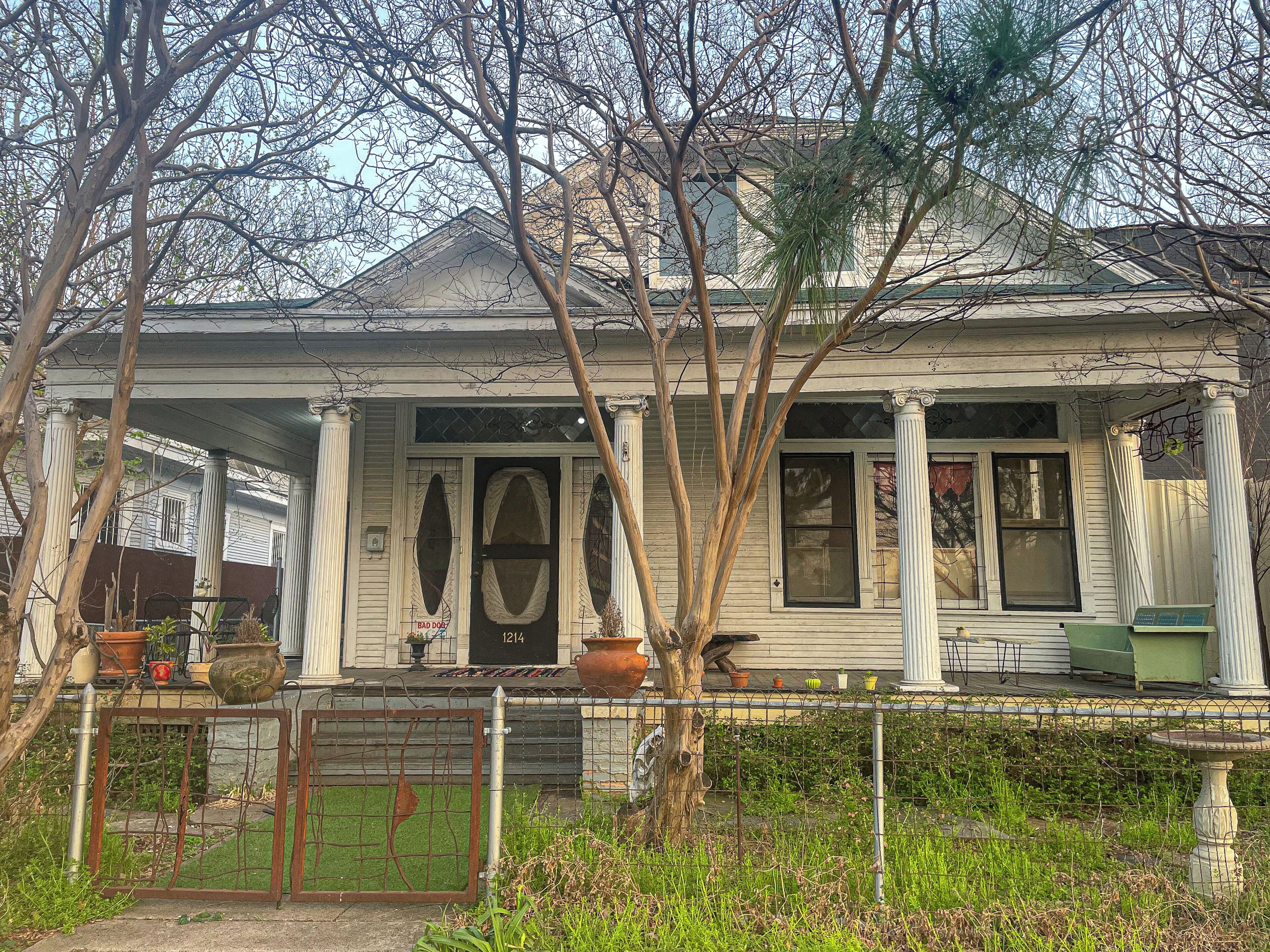A two-story house with a porch, columns, and a number '1214' on the door.