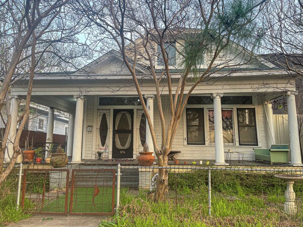 A two-story house with a porch, columns, and a number '1214' on the door.