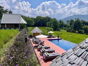 A pool area with lounge chairs and a small pavilion, surrounded by lush greenery and a view of distant mountains. - Kuangsi Resort (Luang Prabang)
