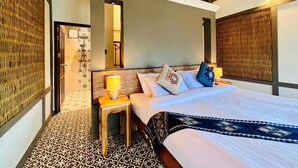 Una habitación de hotel con cama, mesita de noche, lámpara y suelo estampado.