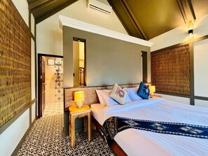 A hotel room with a bed, nightstand, lamp, and patterned floor. - Kuangsi Resort (Luang Prabang)