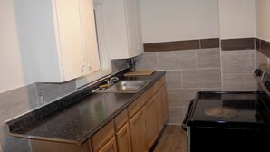 A kitchen with a stove, sink, and wooden cabinets. - Stevenson Motel Federal Way Near I 5 (Federal Way)