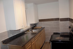A kitchen with a stove, sink, and wooden cabinets.