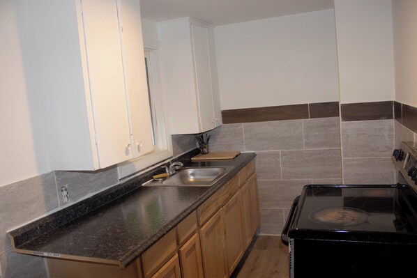 A kitchen with a stove, sink, and wooden cabinets.