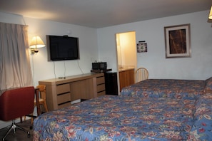 A bedroom with a bed, a desk, a chair, a television, and a microwave.