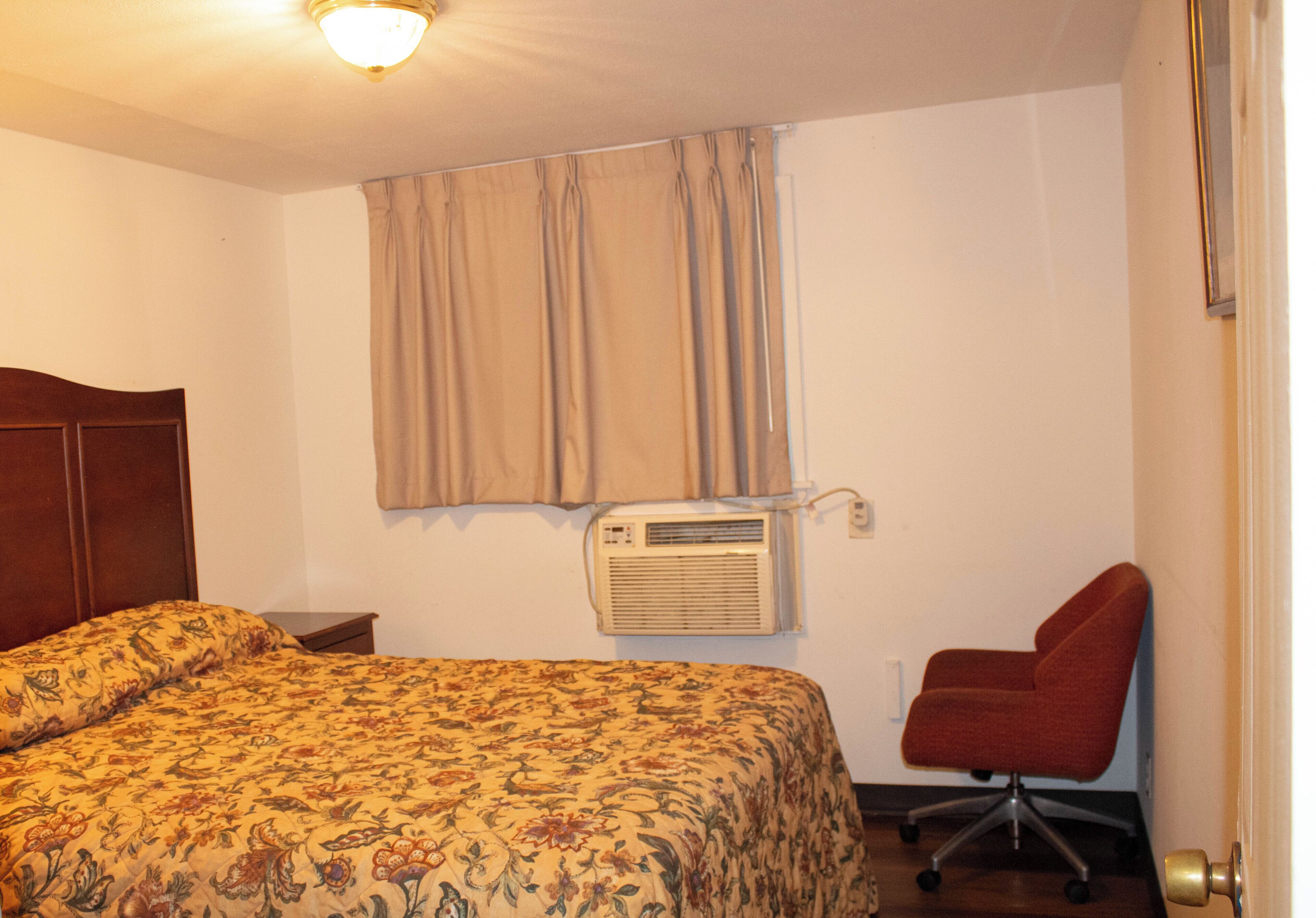 Ein Hotelzimmer mit Bett, Klimaanlage, Stuhl und Tür.
