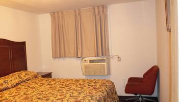 Ein Hotelzimmer mit Bett, Klimaanlage, Stuhl und Tür.