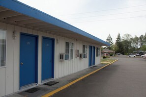 A motel with blue doors numbered 21 and 22, air conditioning units, and a parking lot with cars.
