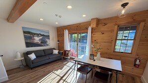 Une pièce chaleureuse avec un plafond en bois, une table à manger avec des chaises, un canapé et un tableau accroché au mur.