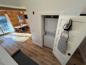 Un cuarto de lavandería con lavadora, secadora y un zapatero.