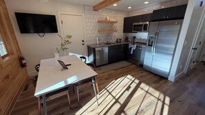 Une cuisine moderne avec une table à manger, un plancher en bois et des appareils électroménagers intégrés.