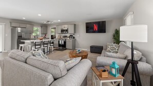 A modern living room with a grey sofa, a coffee table, and a TV mounted on the wall. - Pet Friendly sleeps 10 Fenced Yard Garage Studio (Smithfield)