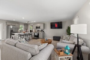 Una sala de estar moderna con un sofá gris, una mesa de centro y un televisor montado en la pared.