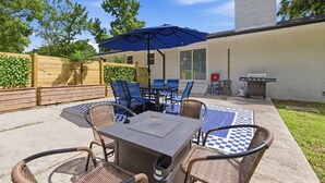 An outdoor patio with a table and chairs, a blue umbrella, and a grill. - Pet Friendly sleeps 10 Fenced Yard Garage Studio (Smithfield)