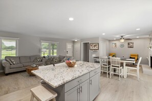 Uma sala ampla com ilha de cozinha, mesa de jantar com cadeiras e um sofá.