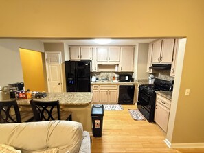 A compact kitchen with a refrigerator, microwave, stove, and dishwasher. - Cozy Townhome in Marietta! (Marietta)