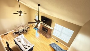 Un loft espacioso con comedor, sofá, chimenea y televisor.