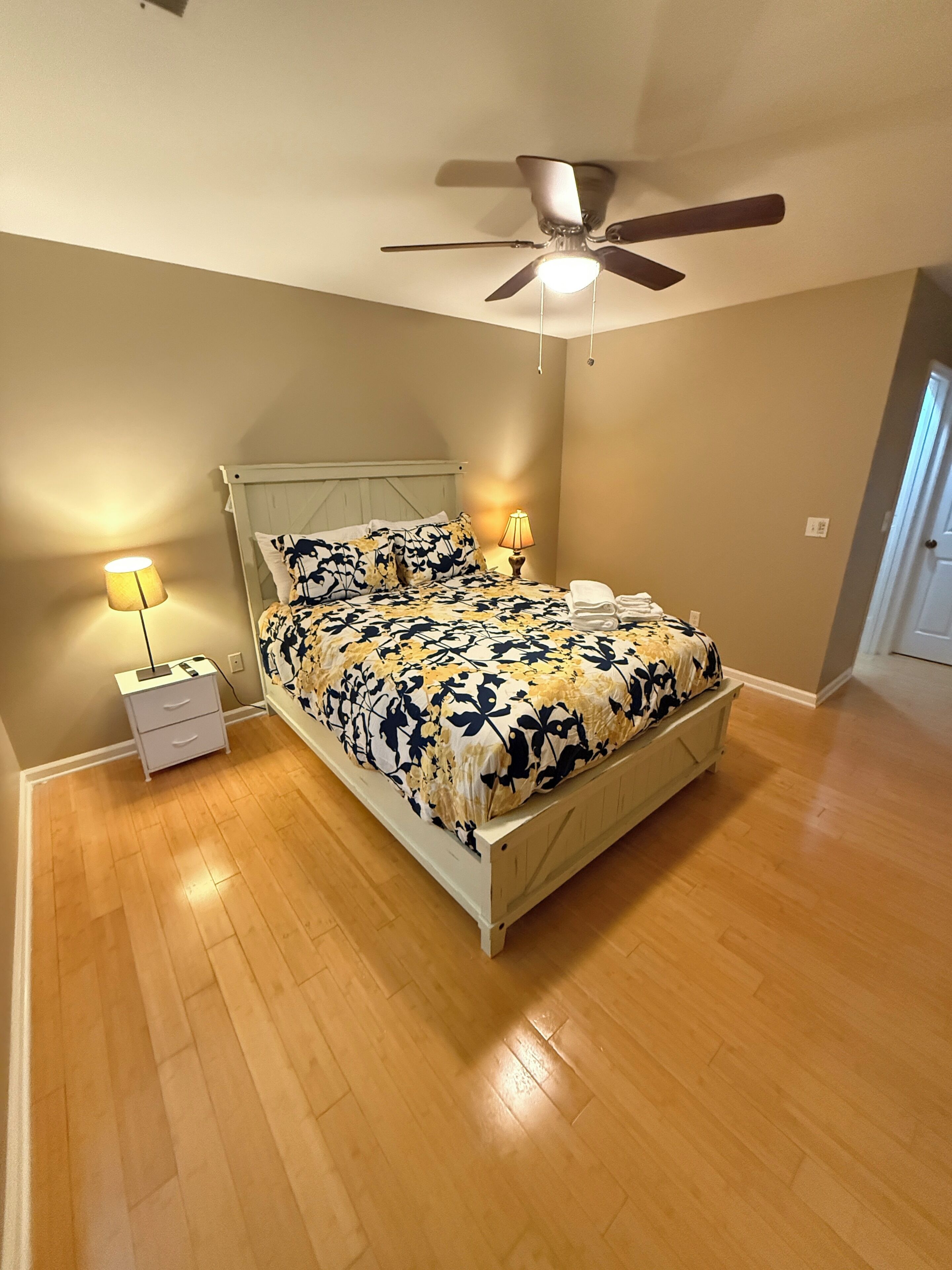 A bedroom with a bed, two bedside tables, a ceiling fan, and a nightstand.